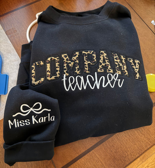 Black sweatshirt with 'Miss Karla' branding on a wooden surface