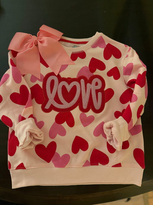 Children's sweater with heart pattern and 'love' text on a dark background