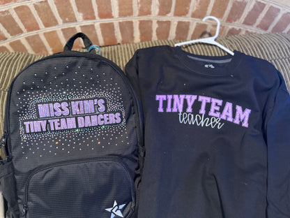 Black backpack and shirt with text on a brick wall background